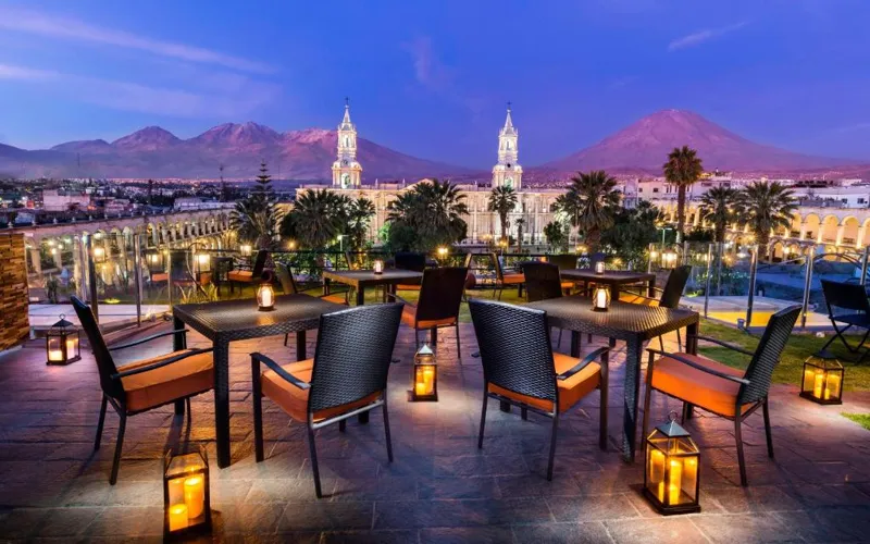 a patio with tables and chairs and a view of a city at Katari Hotel at Plaza de Armas in Arequipa